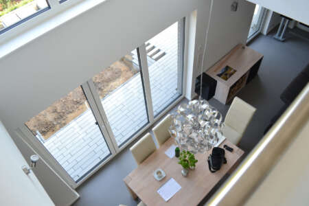 Heller Essbereich mit Designleuchte und bodentiefen Fenstern im modernen Wohnhaus.