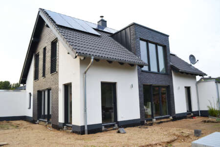 Modernes Einfamilienhaus mit schwarzer Klinkerfassade und Photovoltaikanlage.
